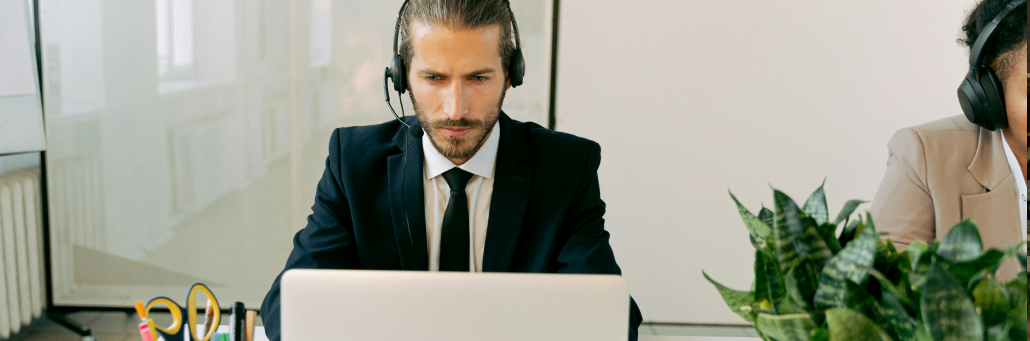 business man lookng at laptop and using headset
