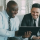 two coworkers looking at laptop screen - AI to fight spam - Fireline Broadband automatic failover