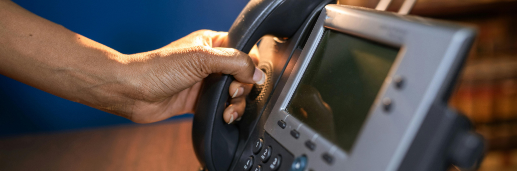 hand picking up business desk phone - Auto attendant - Fireline Broadband